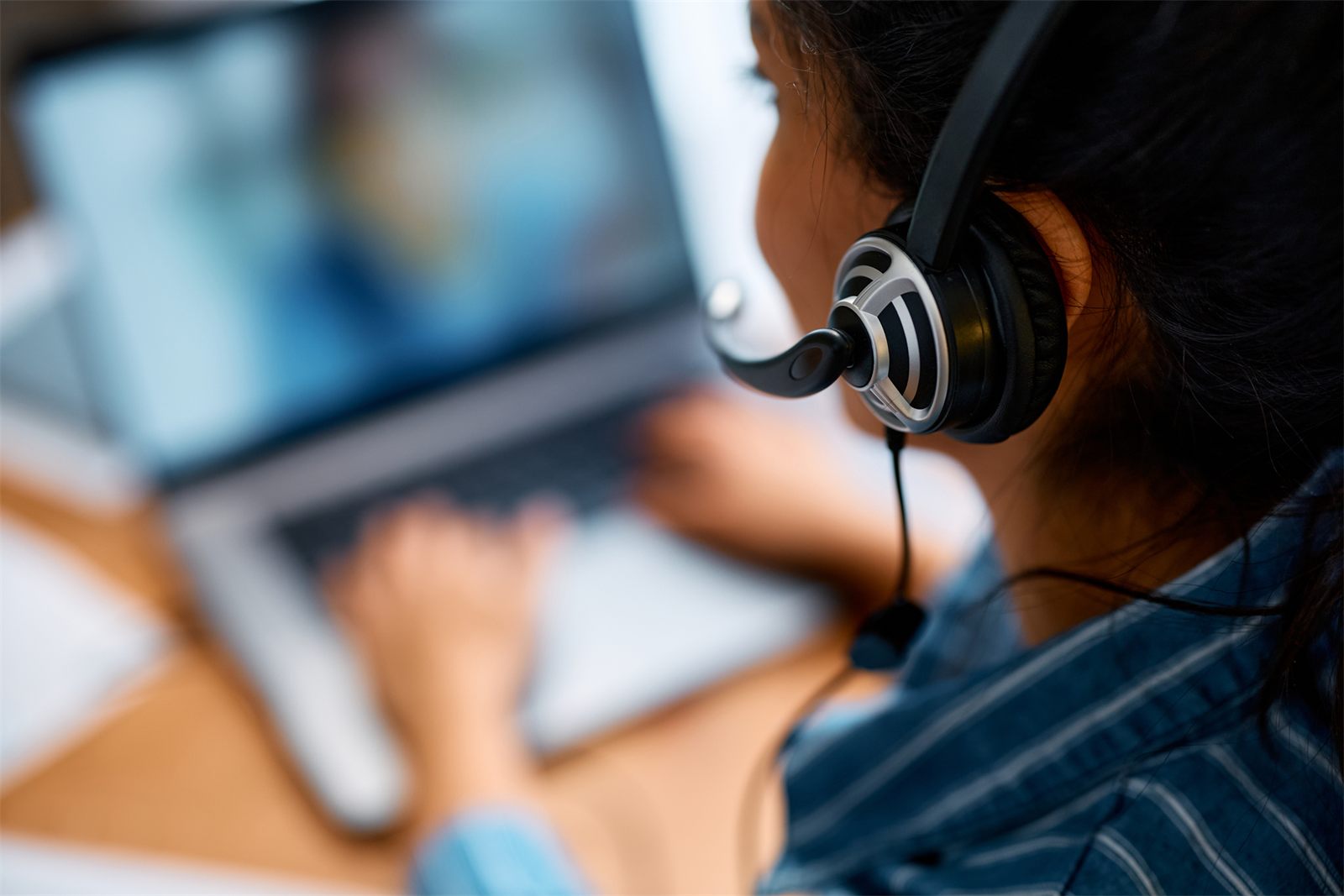 Close-up of a virtual assistant wearing a headset at a laptop