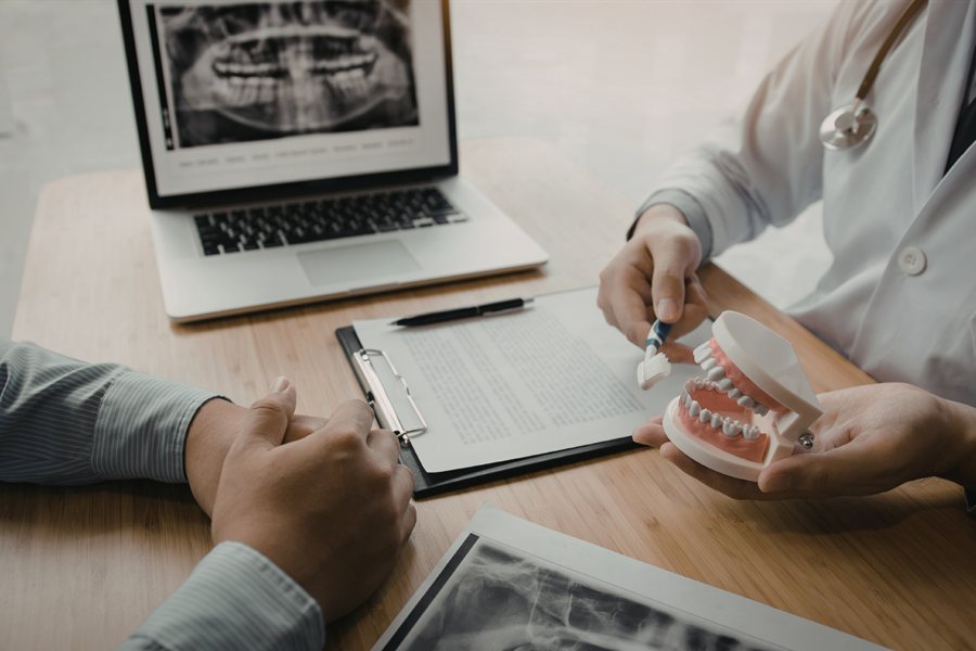 A clinician reviewing scans and notes at a laptop