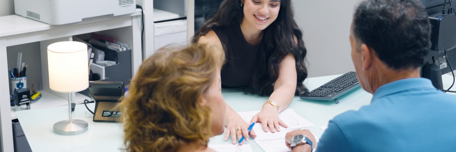A treatment coordinator reviewing paperwork with two patients